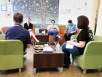 5 people sitting in chairs chatting and eating some lunch.