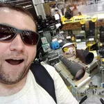 Smiling man in front of a lot of camera accessories.